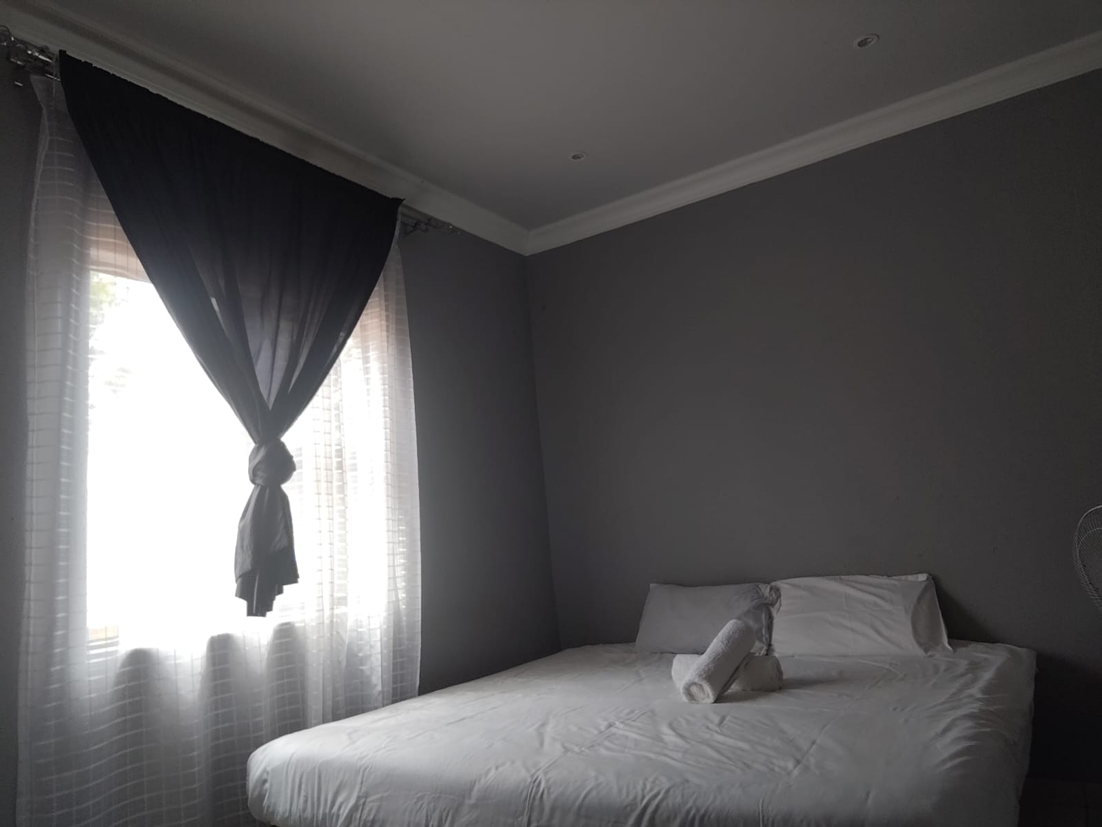 Apartment bed beside a curtained window